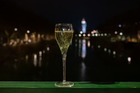 Tasting of french sparkling white wine with bubbles champagne outdoor at night with view on Marne river and lights of Epernay city in winter, Franceの写真素材