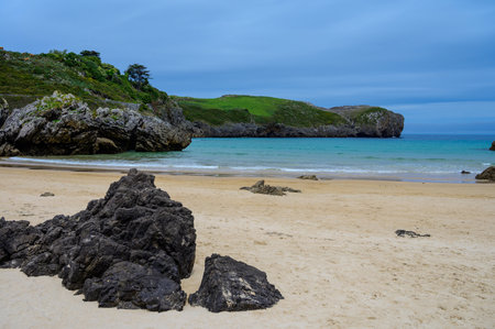 View on rocks on Playa de Borizo in Celorio, Green coast of Asturias, North Spain with white sandy beaches, cliffs, hidden caves, green fields, forests and mountains.の写真素材