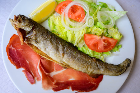 Main dish in Asturian restaurant, grilled whole trout fish from mountain river served with fresh...