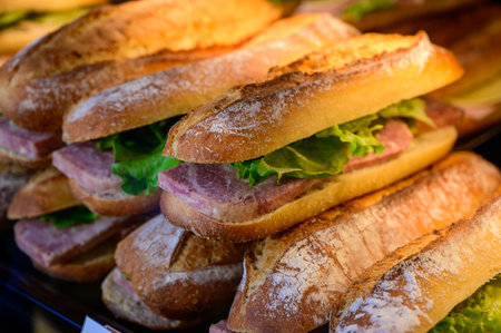 Fresh made organic sandwiches with baquette buns, bacon and salad, english translation is bacon, on display in bakery in Franceの写真素材