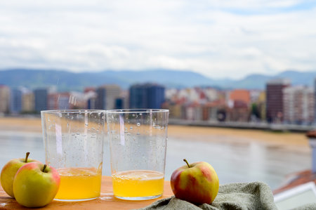 Traditional natural Asturian cider made from fermented apples in wooden barrel should be poured from great height for air bubbles into the drink and view on San Lorenzo beach of Gijonの写真素材