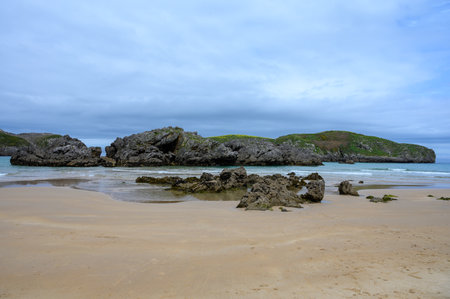 View on rocks on Playa de Borizo in Celorio, Green coast of Asturias, North Spain with white sandy beaches, cliffs, hidden caves, green fields, forests and mountains.の写真素材
