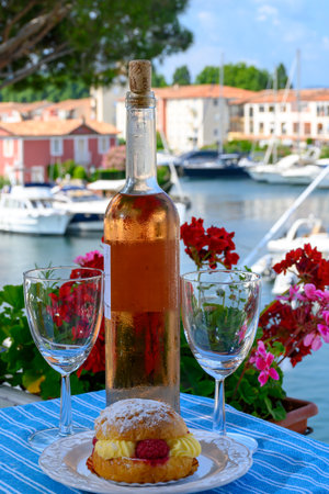 Wine and cakes of French Riviera, glasses of cold rose Cote de Provence wine and Tarte Tropezienne cake in yacht harbor of Port Grimaud, summer vacation in Provence, Franceの写真素材