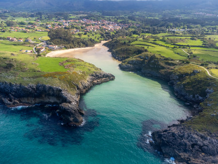Aerial view on Playa de Poo during low tide near Llanes, Green coast of Asturias, North Spain with white sandy beaches, cliffs, hidden caves, green fields and mountains.の写真素材