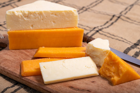 British cheeses collection, Scottish colored and English matured cheddar cheeses close up.
