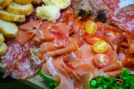 Fresh cuts of French cured sausages, ham, cheeses, tomatoes for party close upの写真素材