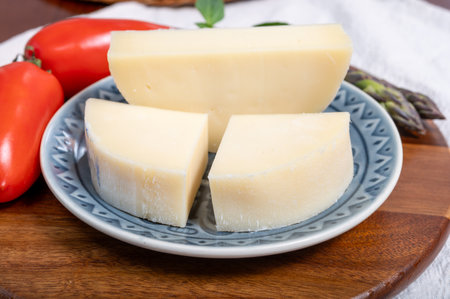 Italian cheese, Provolone dolce cow cheese from Cremona served with olive bread and tomatoes close up.の写真素材