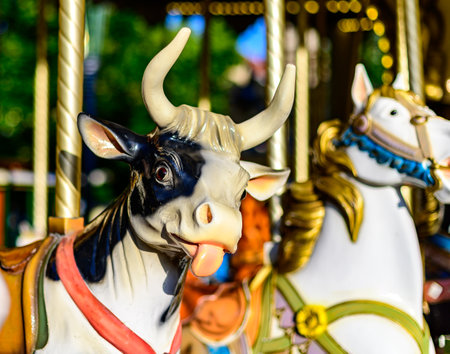 Colorful cow on traditional old french carousel in city park in sunny day, Troys, Champagne, Franceの写真素材