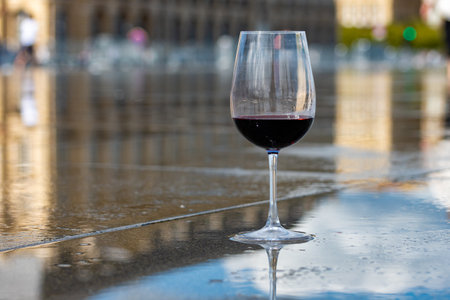 Tasting of Bordeaux blended red wine and view on city Bordeaux on background, left bank of Gironde Estuary, France. Glass of red French wine.の写真素材