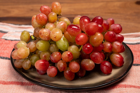 Sweet washed ripe pink grapes berries on board ready to eat close up