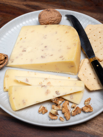 Piece of Dutch Gouda cheese made from cow milk with added walnuts close up, cheese tasting on farm