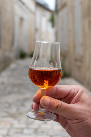 Tasting of aged in barrels cognac alcohol drink and view on old streets and houses in town Cognac, Grand Champagne, Charente, strong spirits distillation industry, Franceの写真素材