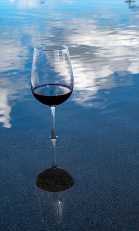 Tasting of Bordeaux blended red wine with wine city Bordeaux on background, left bank of Gironde Estuary, France. Glass of red French wine served outdoor.の写真素材