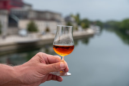 Tasting of aged in barrels cognac alcohol drink and view on old streets and houses in town Cognac, Grand Champagne, Charente, strong spirits distillation industry, Franceの写真素材