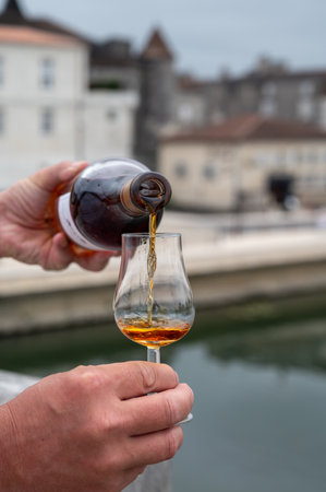 Tasting of aged in barrels cognac alcohol drink and view on old streets and houses in town Cognac, Grand Champagne, Charente, strong spirits distillation industry, Franceの写真素材