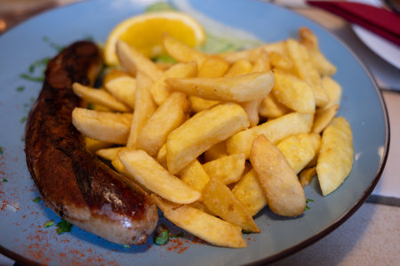 Fried fries potatoes with grilled meat German sausage served in old restaurant in Germany cloaw upの写真素材