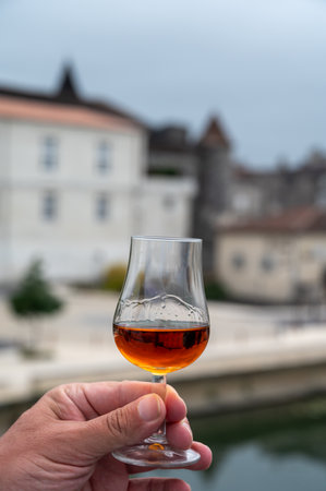 Tasting of aged in barrels cognac alcohol drink and view on old streets and houses in town Cognac, Grand Champagne, Charente, strong spirits distillation industry, Franceの写真素材