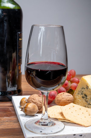 Red porto and cheese pairing, blue matured stilton English cheese served as dessert with walnuts and glass ruby porto wine close upの写真素材