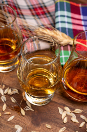 Tasting of different Scotch whiskeys strong alcoholic drinks, drum glass of whiskey and colorful Scotch tartan on background close upの写真素材