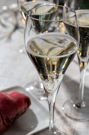 New year party, small bubbles of brut champagne cava or prosecco wine in tulip glasses with garland lights on dark backgroundの写真素材