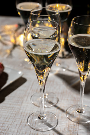 New year party, small bubbles of brut champagne cava or prosecco wine in tulip glasses with garland lights on dark backgroundの写真素材