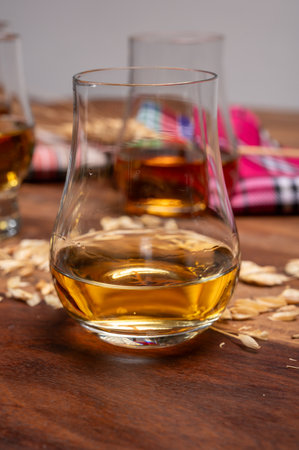Tasting of different Scotch whiskeys strong alcoholic drinks, drum glass of whiskey and colorful Scotch tartan on background close upの写真素材