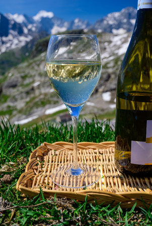Glass and bottle of dry white Roussette de Savoie or Vin de Savoie wine from Savoy region served on Col du Galibier border Savoy region, France, view on Alpes mountains.の写真素材