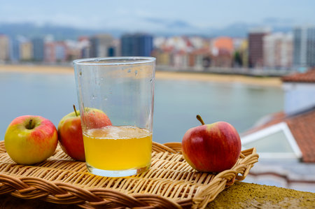 Traditional natural Asturian cider made from fermented apples in wooden barrel should be poured from great height for air bubbles into the drink and view on San Lorenzo beach of Gijonの写真素材