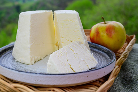 Spanish Afuega'l pitu unpasteurized cow's milk cheese from Asturias served outdoor with apples and view on green slopes of Picos de Europa mountains, Spainの写真素材