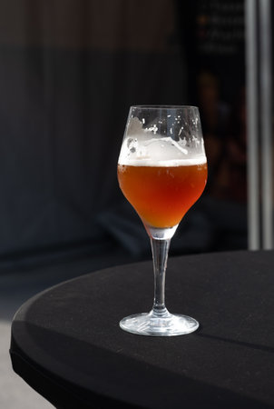 Famous fresh brewed red lambic kriek cherry beer served outside in Belgian beer festival in Durbuy, special Belgian beer glass in sun lights, close upの写真素材