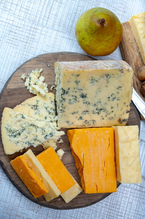 English cheeses collection, mature and colored cheddar cheese and semi-soft, crumbly old stilton...