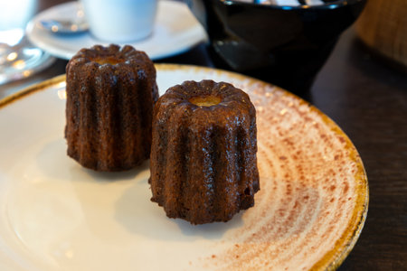Canele, French pastry flavored with rum and vanilla, specialty of Bordeaux region, France, served on white plate with cup of black coffee in French restaurantの写真素材