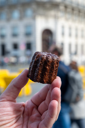 Canele, French pastry flavored with rum and vanilla, soft and tender custard center and dark, caramelized crust specialty of Bordeaux region, France and streets of Bordeaux on backgroundの写真素材