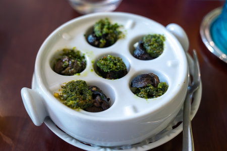 Starter dish in traditional restaurants on Burgundy, snails cooked with butter, garlic and herbs, France served on white porcelain plateの写真素材