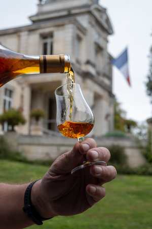 Tasting of aged in barrels cognac alcohol drink and view on old streets and houses in town Cognac, Grand Champagne, Charente, strong spirits distillation industry, Franceの写真素材