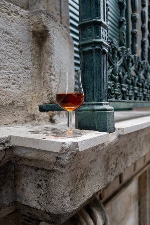 Tasting of aged in barrels cognac alcohol drink and view on old streets and houses in town Cognac, Grand Champagne, Charente, strong spirits distillation industry, Franceの写真素材