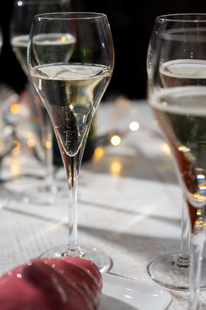 New year party, small bubbles of brut champagne cava or prosecco wine in tulip glasses with garland lights on dark backgroundの写真素材