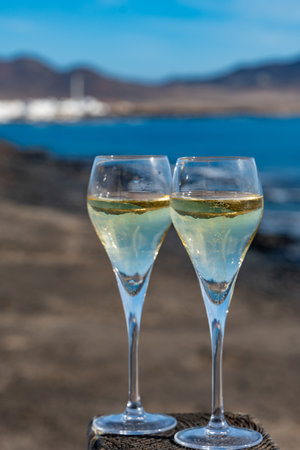 Pouring a glass of champagne on vacation, south of Fuerteventura, Canary islands, blue ocean, mountains, Spainの写真素材