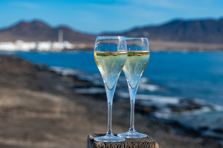 Pouring a glass of champagne on vacation, south of Fuerteventura, Canary islands, blue ocean, mountains, Spainの写真素材