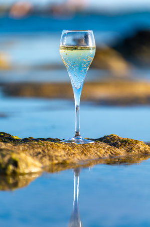 Glass of cava or champagne sparkling wine, winter vacation, low tide on Dunes Corralejo sandy beach, Fuerteventura, Canary islands, Spainの写真素材