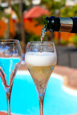 Pouring a glass of champagne on vacation, south of Fuerteventura, Canary islands, blue ocean, mountains, Spainの写真素材