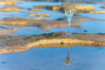 Glass of cava or champagne sparkling wine, winter vacation, low tide on Dunes Corralejo sandy beach, Fuerteventura, Canary islands, Spainの写真素材