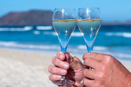 Pouring a glass of champagne on vacation, south of Fuerteventura, Canary islands, blue ocean, mountains, Spainの写真素材