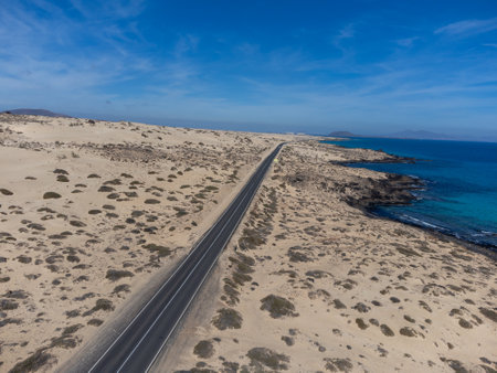 Driving car on black asphalt road through white sandy dunes near Corralejo beach at colorful sunset Fuerteventura, Canary islands, Spain in winterの写真素材