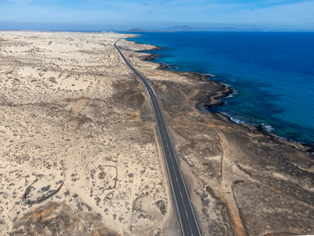 Driving car on black asphalt road through white sandy dunes near Corralejo beach at colorful sunset Fuerteventura, Canary islands, Spain in winterの写真素材