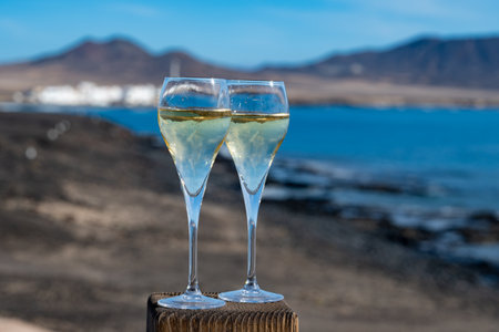 Pouring a glass of champagne on vacation, south of Fuerteventura, Canary islands, blue ocean, mountains, Spainの写真素材