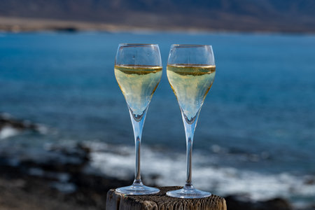 Pouring a glass of champagne on vacation, south of Fuerteventura, Canary islands, blue ocean, mountains, Spainの写真素材