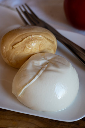 Tasty Italian food, small balls of smoked and white mozzarella soft cheese served on white boardの写真素材