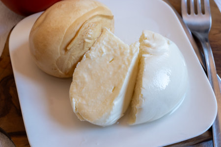 Tasty Italian food, small balls of smoked and white mozzarella soft cheese served on white boardの写真素材