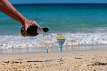 Pouring a glass of champagne on vacation, south of Fuerteventura, Canary islands, blue ocean, mountains, Spainの写真素材